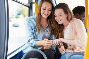 Two Young Women Listening To Music On Bus