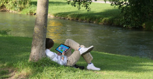 young-man-reading-tablet-by-river